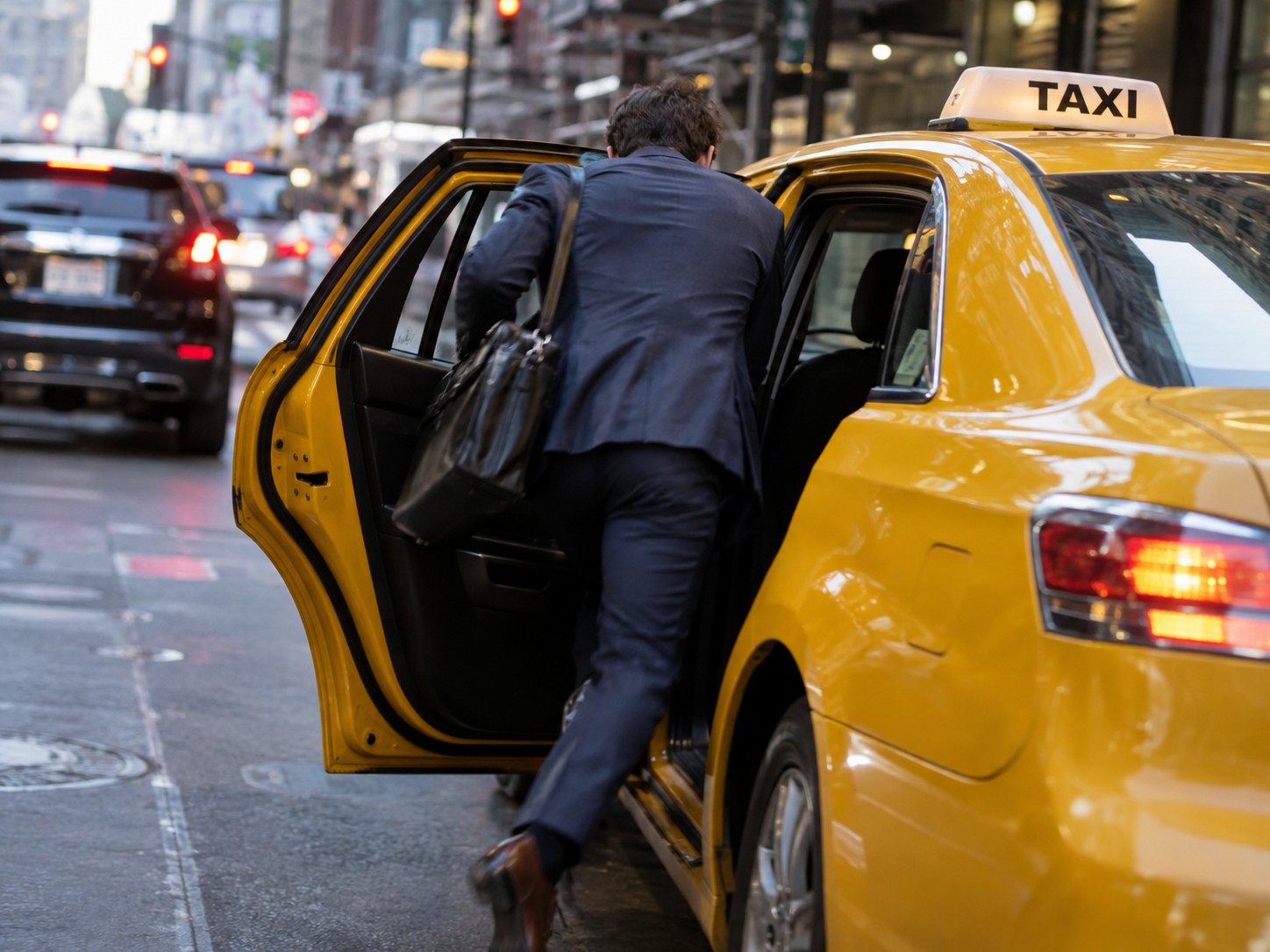 Ein Fahrgast steigt auf einer Stadtstraße in ein gelbes Taxi ein